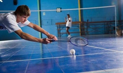 The player stretches his body to make a return in badminton